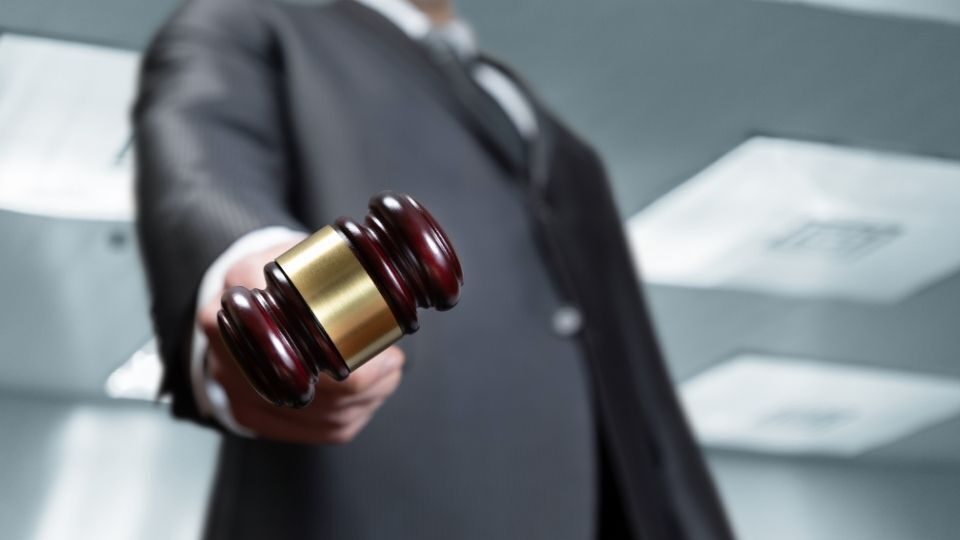 (In the image it can be seen a businessman is holding a gavel in his hand symbolising commercial dispute and litigation)