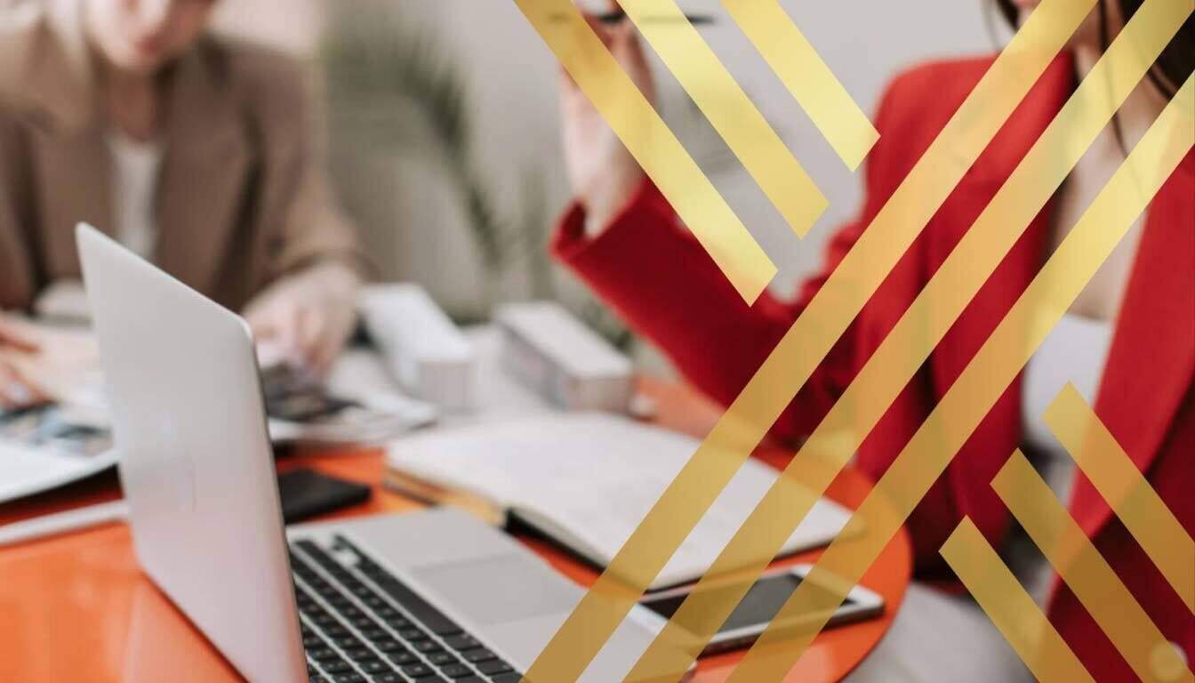 Blurred image of two professionals working on a laptop, representing high-skilled workers or planning immigration strategy for ILR Eligibility