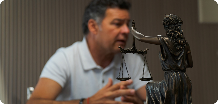 A man gazes thoughtfully at a statue of Lady Justice, symbolizing fairness and the rule of law.