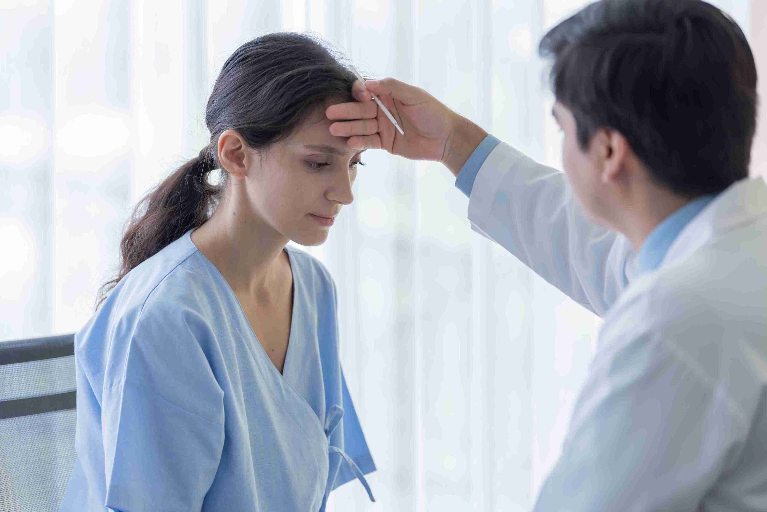 A doctor examines a woman's forehead, highlighting the importance of clinical negligence awareness in patient care.