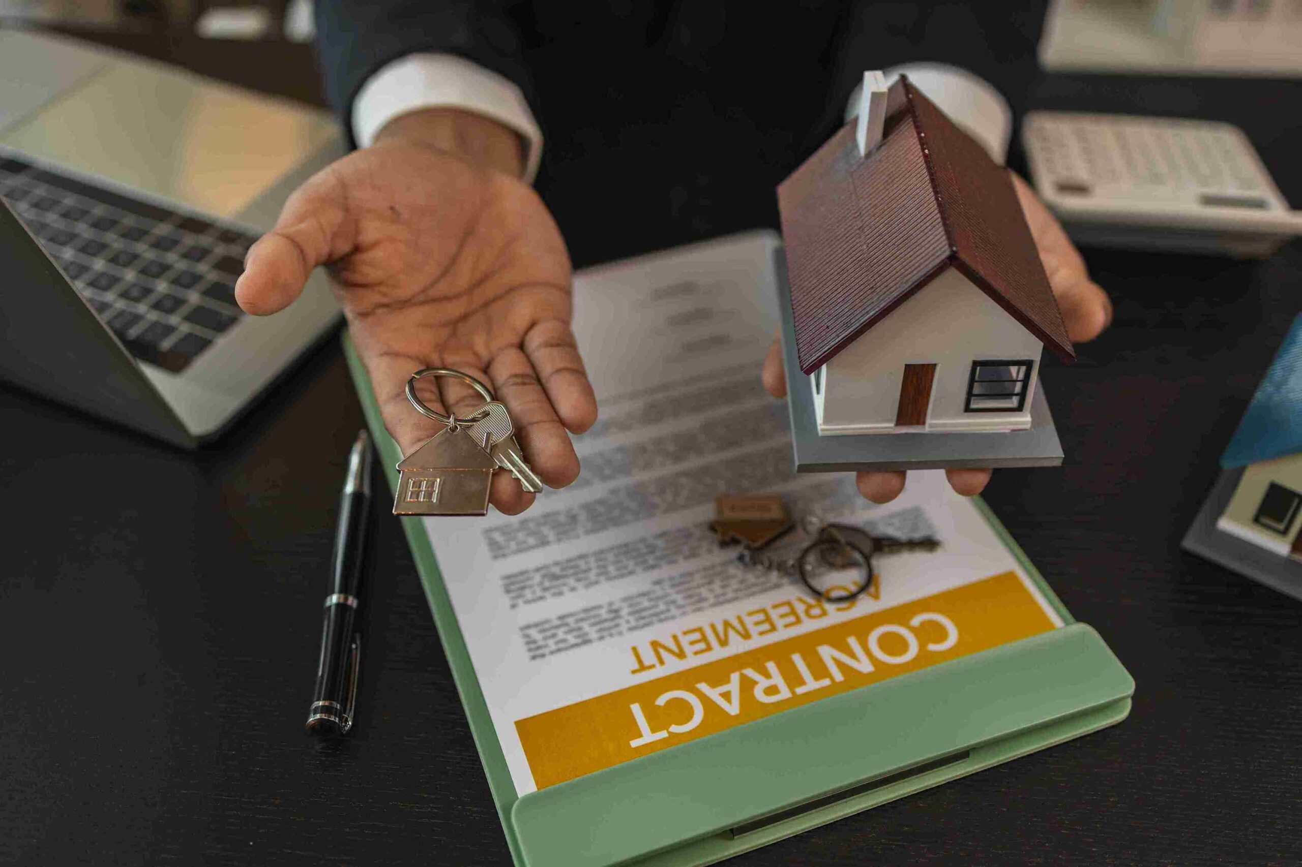 A real estate agent smiles while holding a house model and keys, representing landlord legal support services.