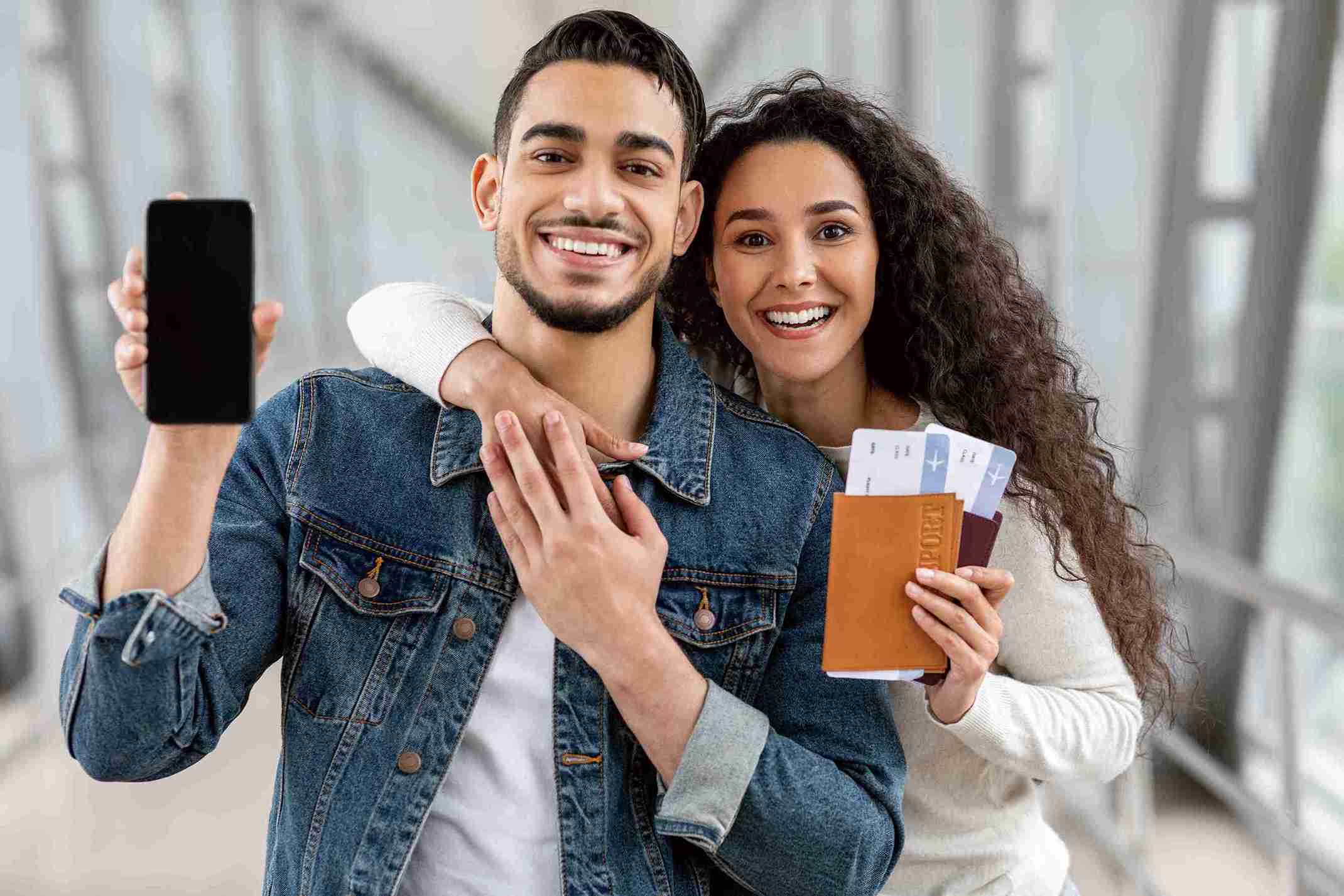 A man and woman smile while holding their passports