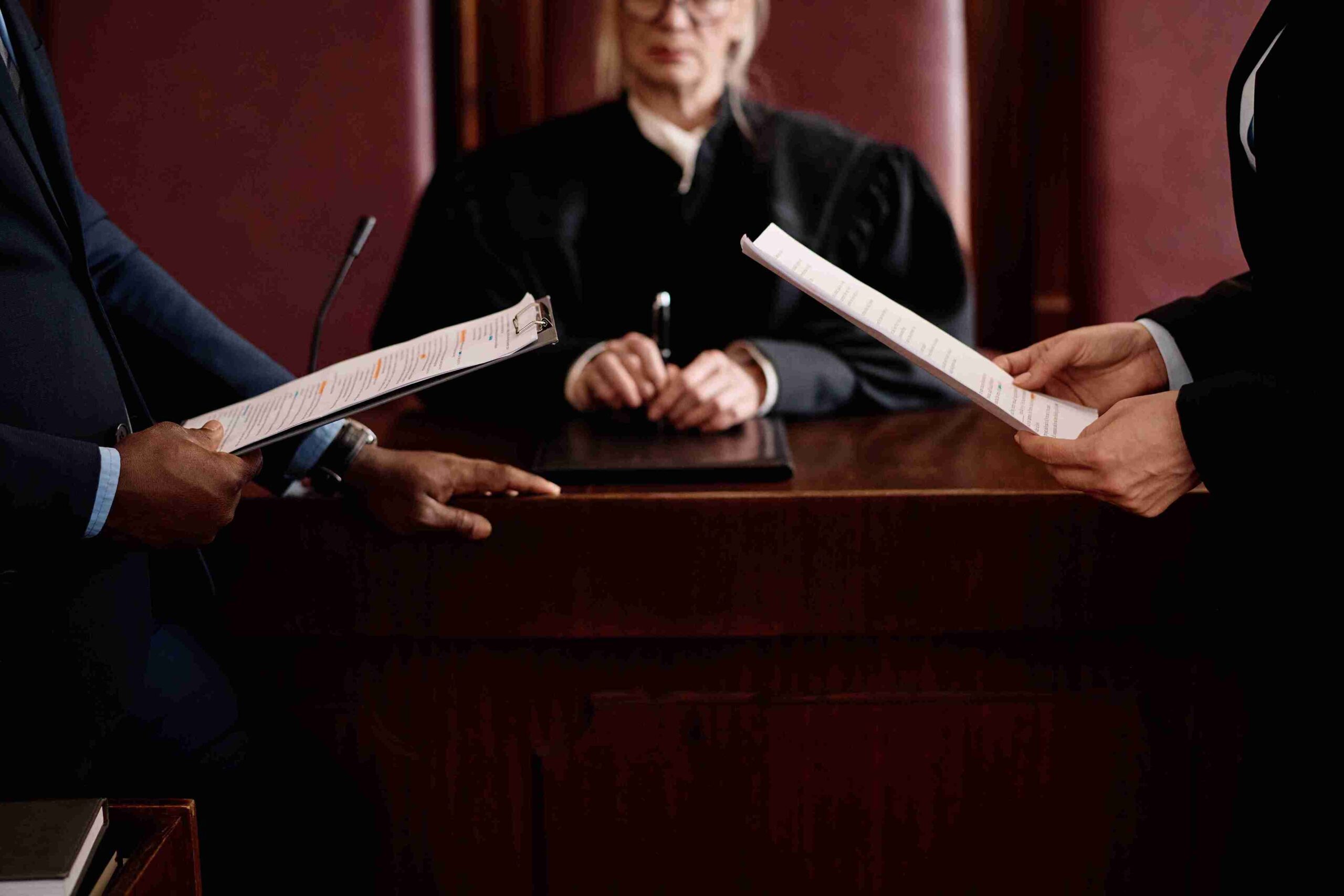 Two people in suits discuss Non-Molestation Orders in front of a judge in a courtroom setting.