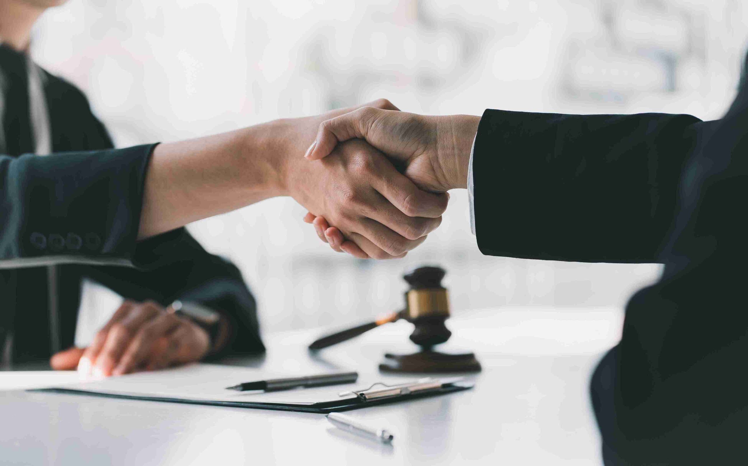 Two people shaking hands over a table, symbolizing expert legal advice for tenants facing property challenges.