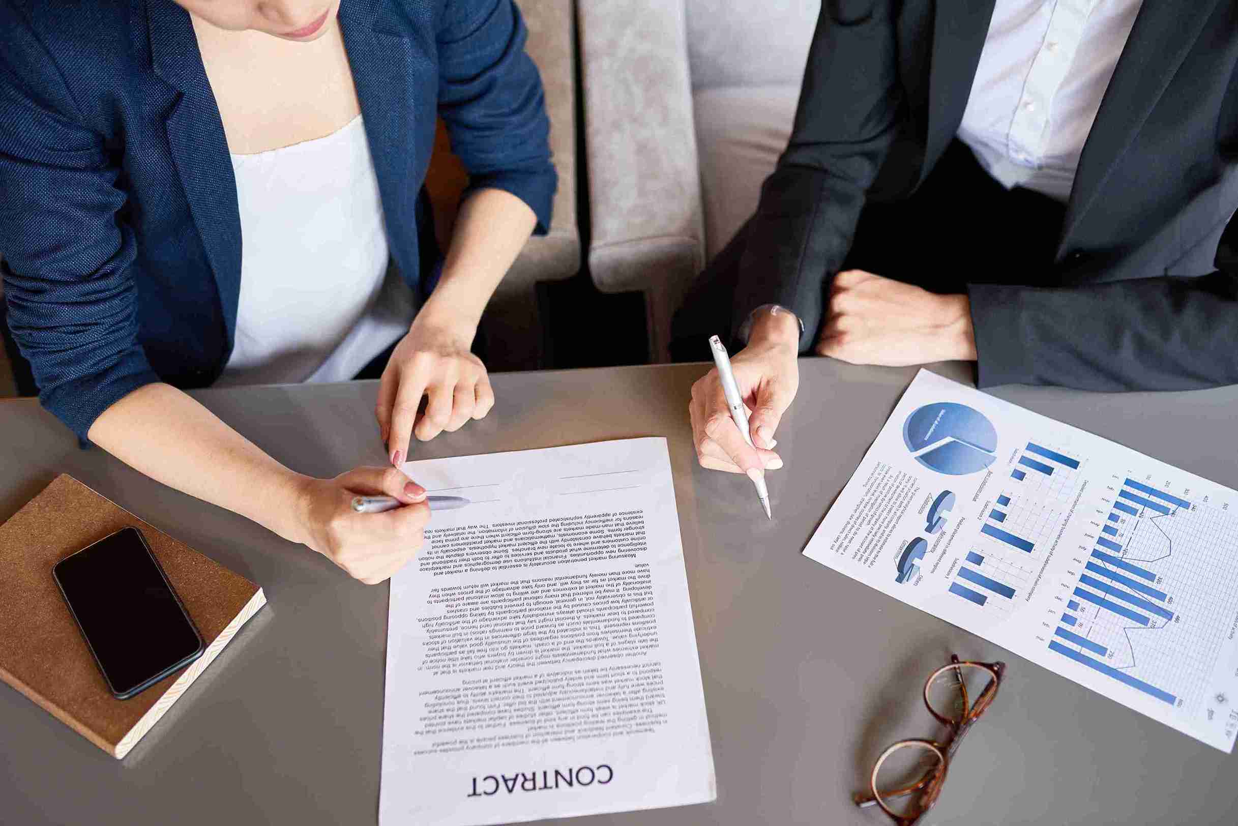 Two business people at a table with papers and pens, discussing and sign the Certificates of Sponsorship