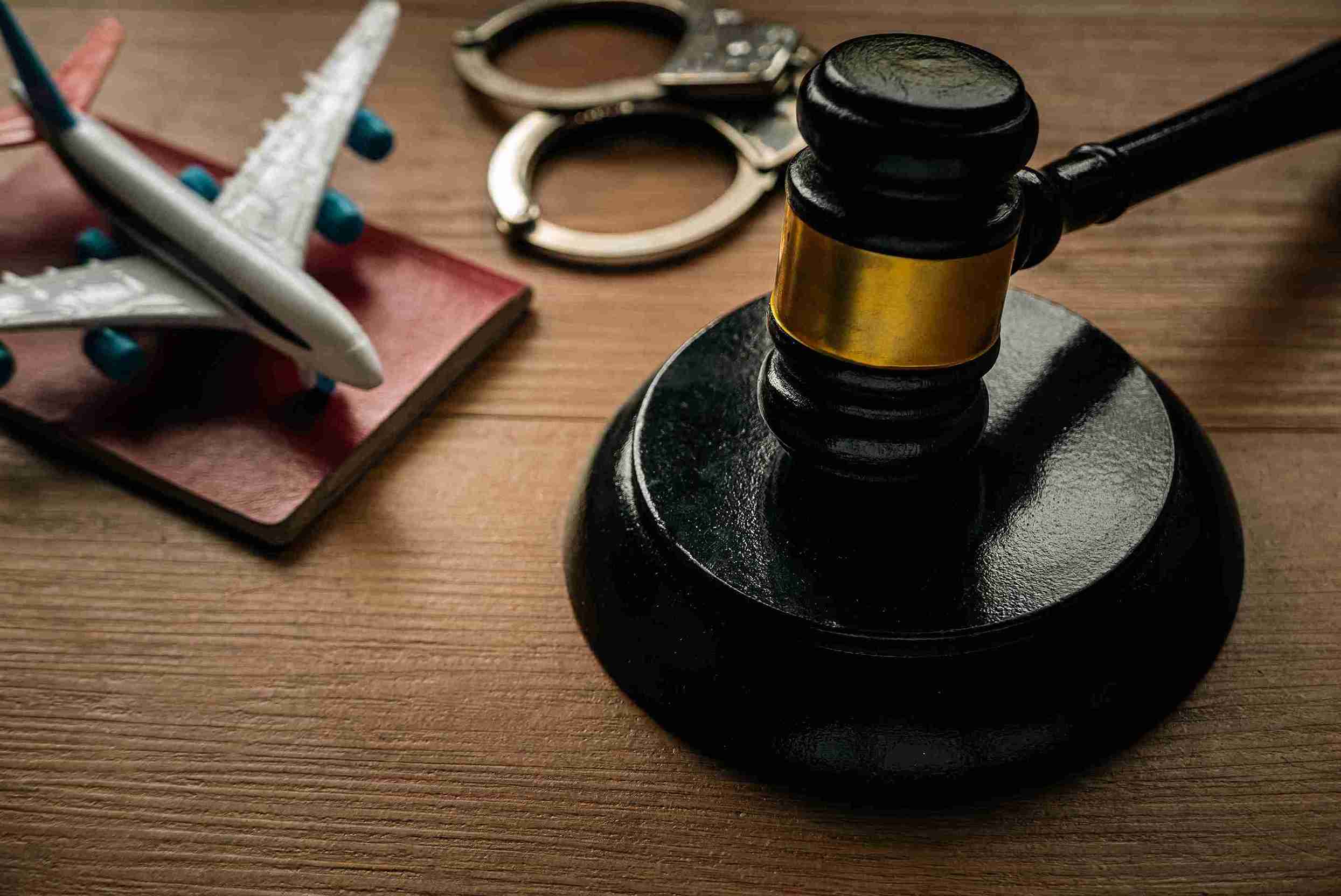 A judge's gavel and a toy airplane rest on a wooden table, symbolizing justice and immigration themes.