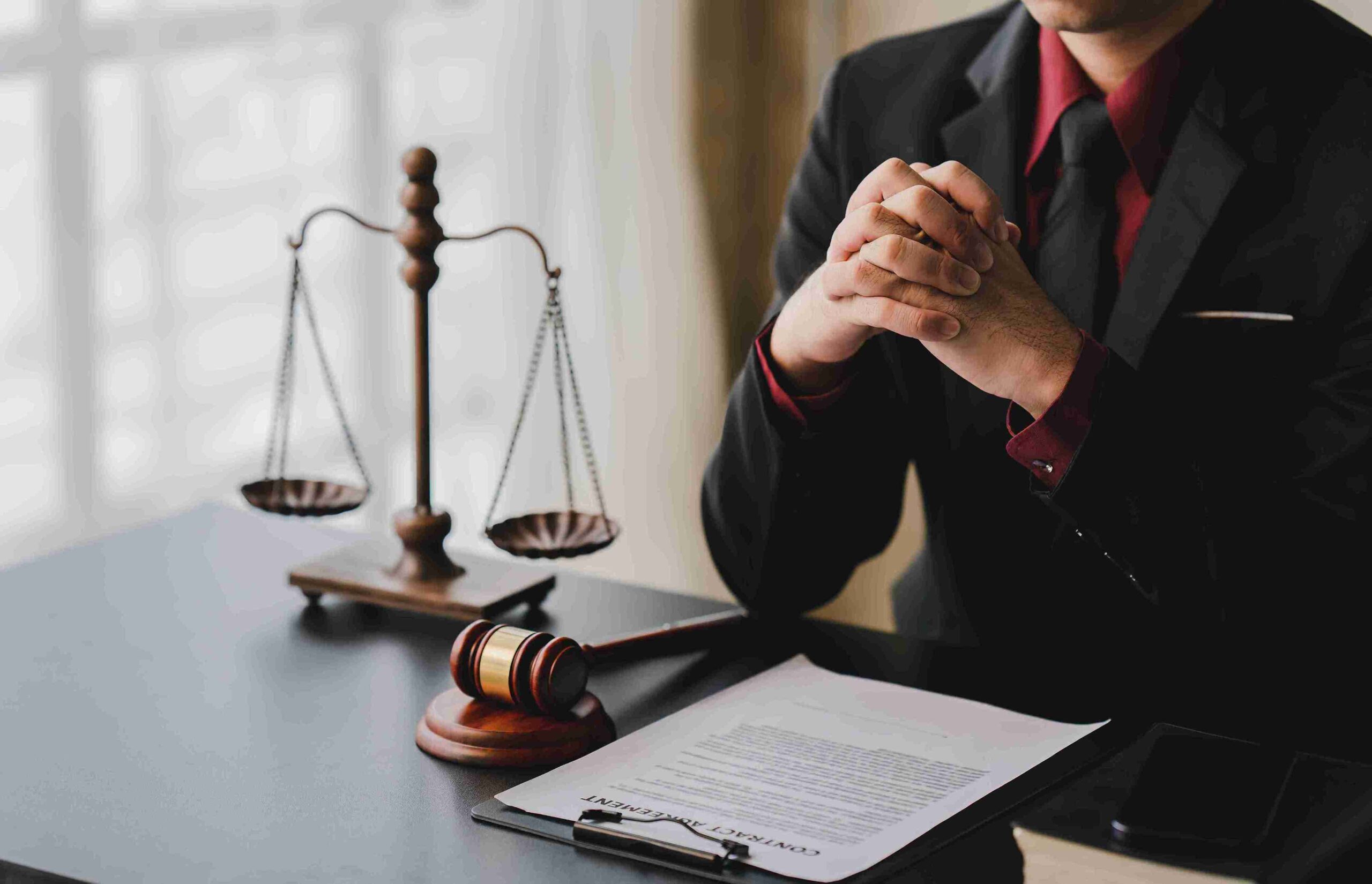 Person in suit at desk with gavel, legal document, and scales, representing expert tribunal representation to handle disputes and protect professional standing.