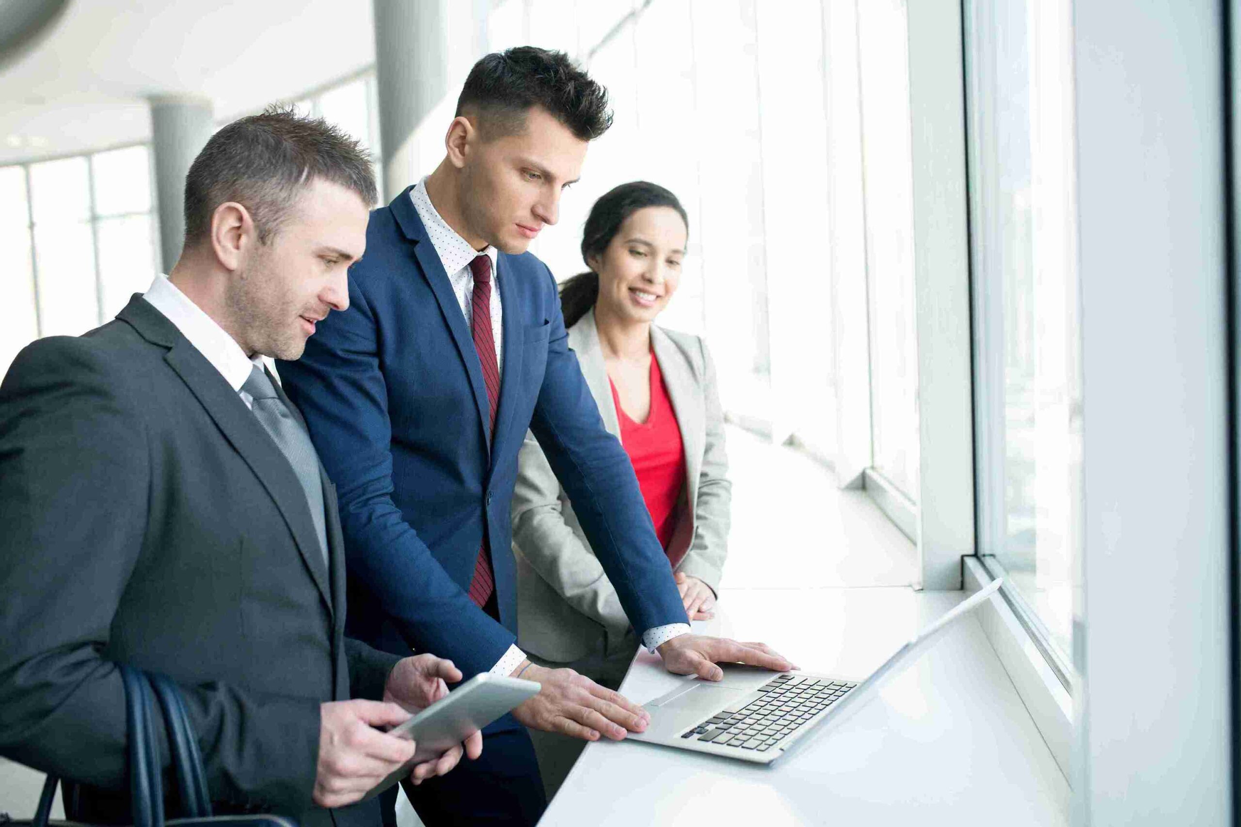 Three business professionals collaborating over a laptop, sending the UK's Global visa for temporary assignments.