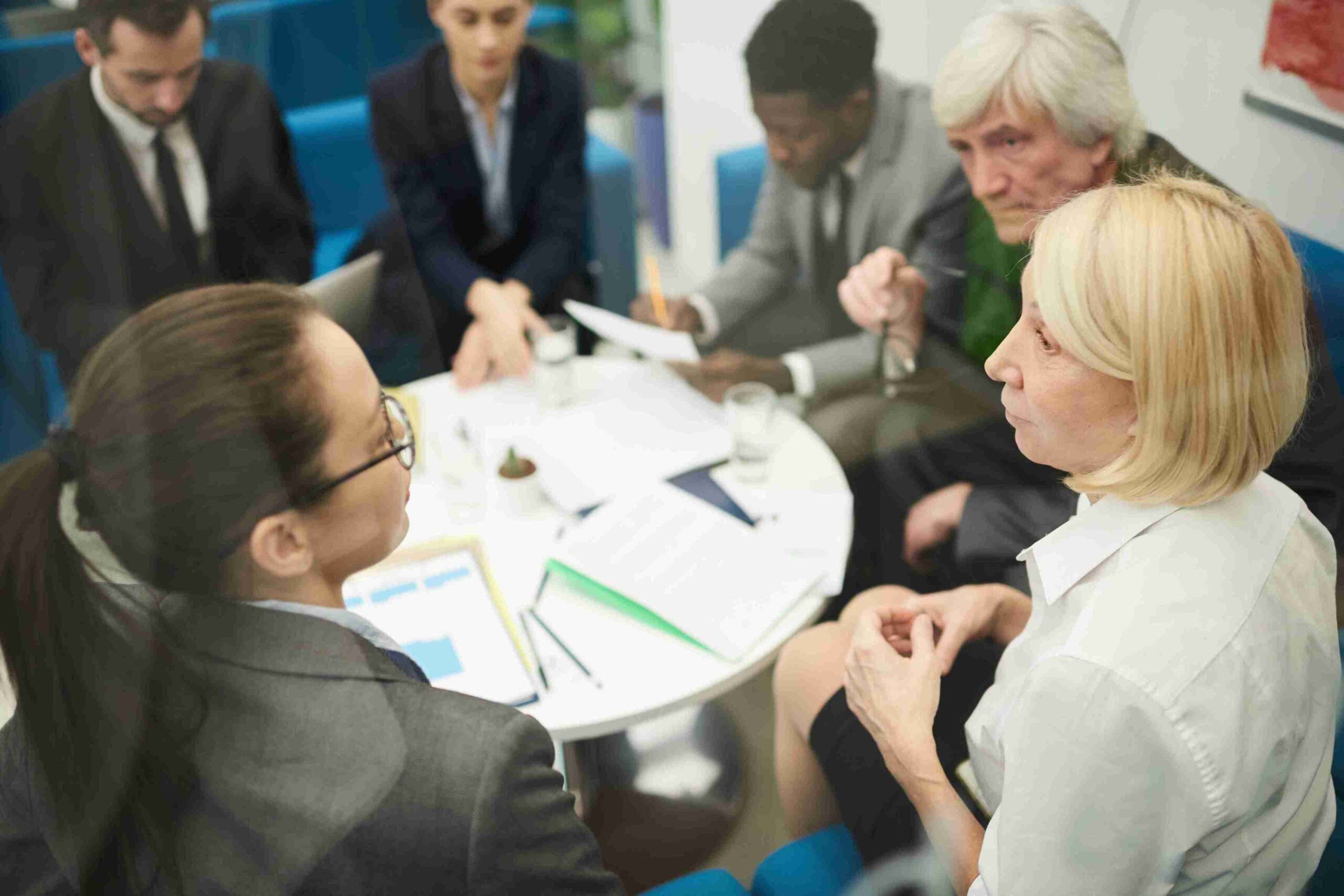 A group of business people discussing key personnel appointments around a table, utilizing the Sponsorship Management System.