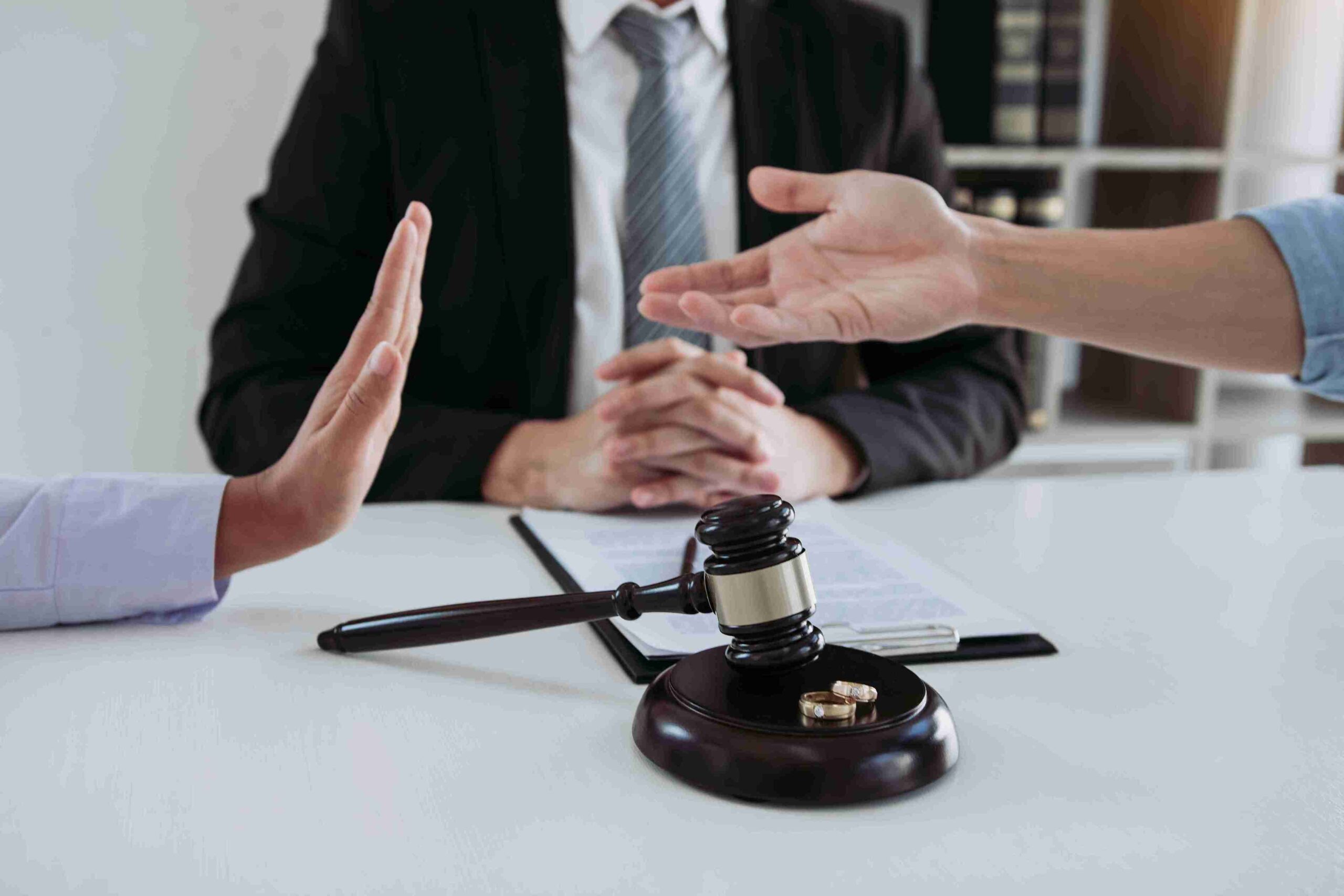 A judge and a lawyer discuss matrimonial asset disputes at a table, with a gavel placed prominently between them.
