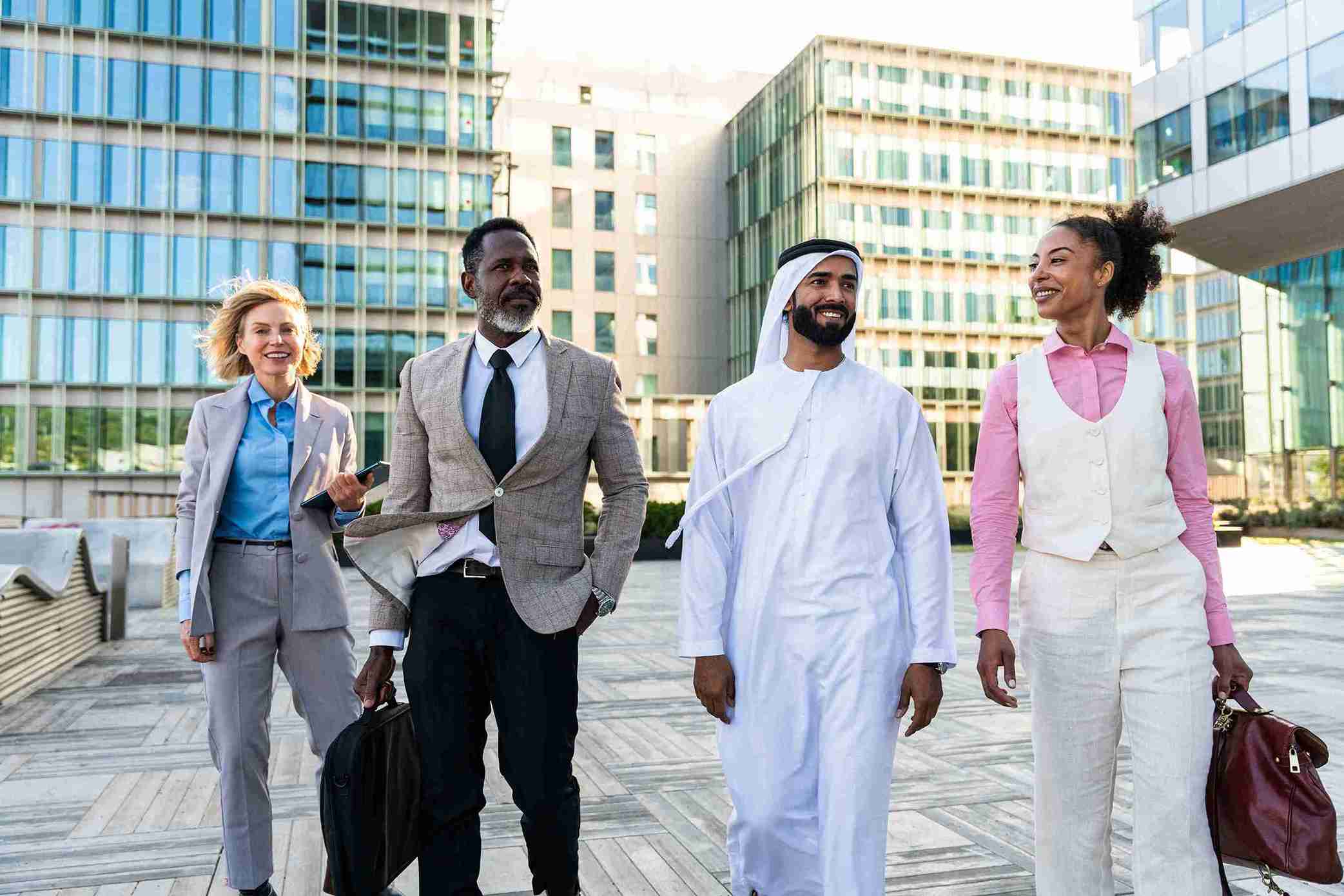 Arabic business people walking in a UK city, discussing immigration and business opportunities.