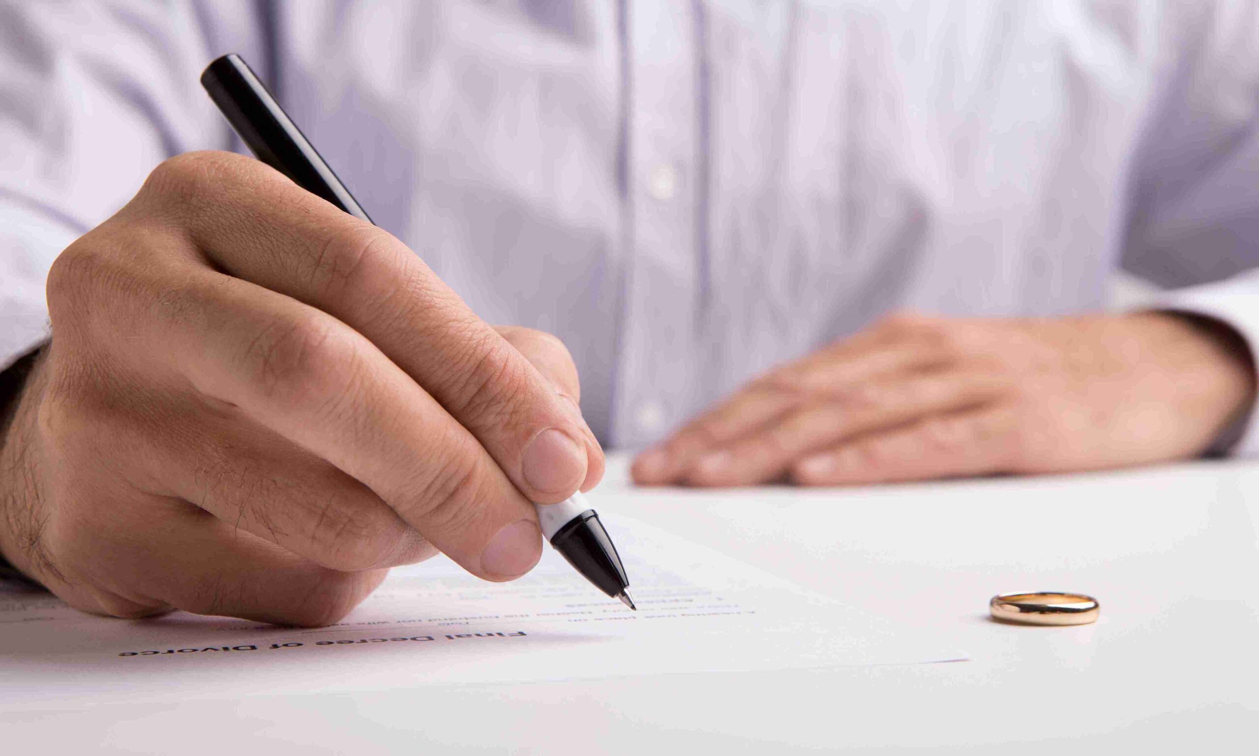 A man signing a divorce paper, focused on the document with a serious expression.