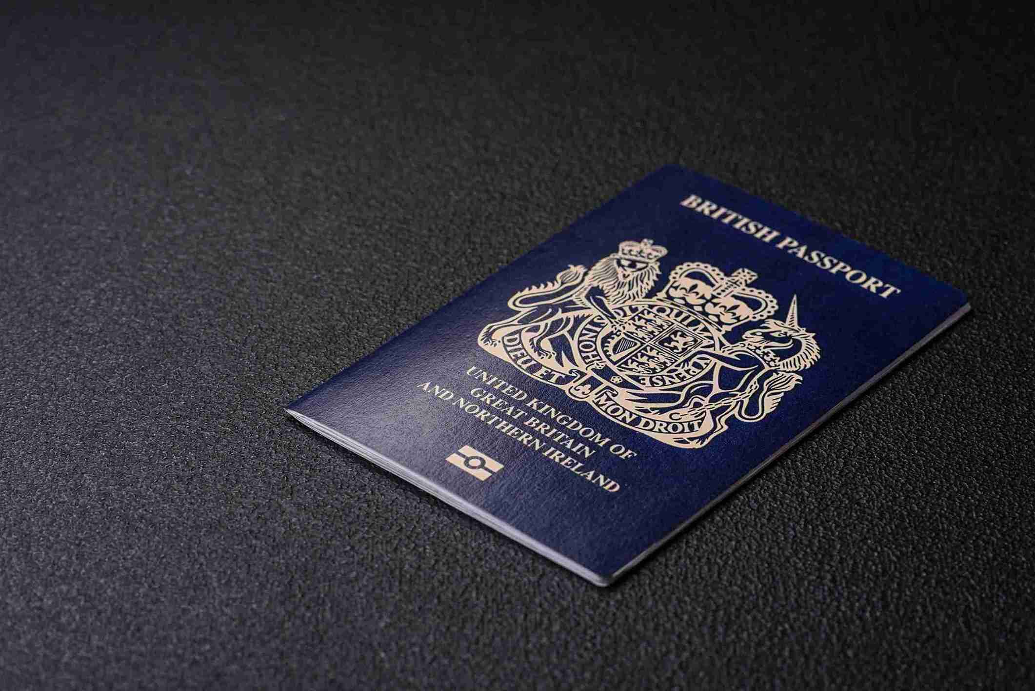 A British passport resting on a sleek black surface, showcasing its distinctive cover and emblem.