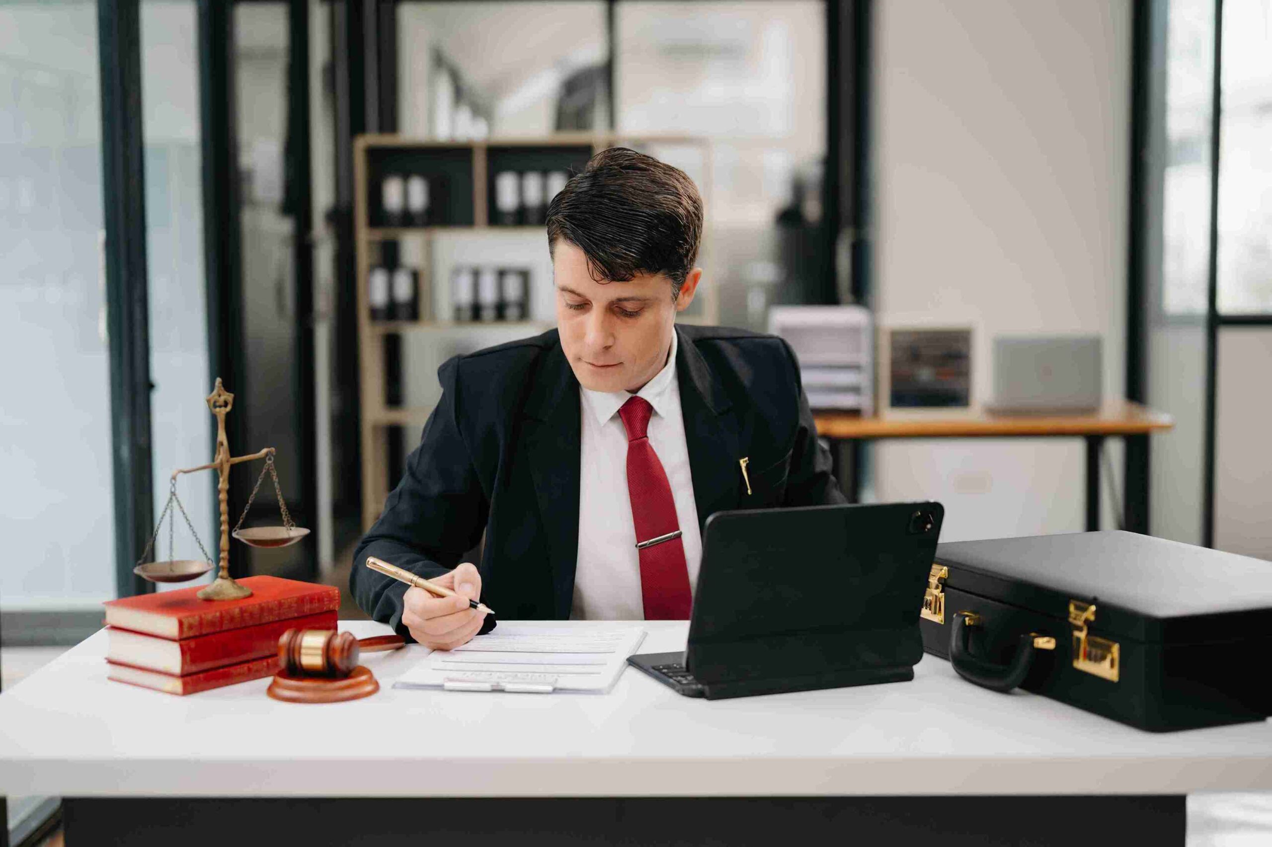 Man in suit working at desk with law books, gavel, and laptop, representing strong tax compliance, accurate record keeping, and proactive steps to prevent investigations.