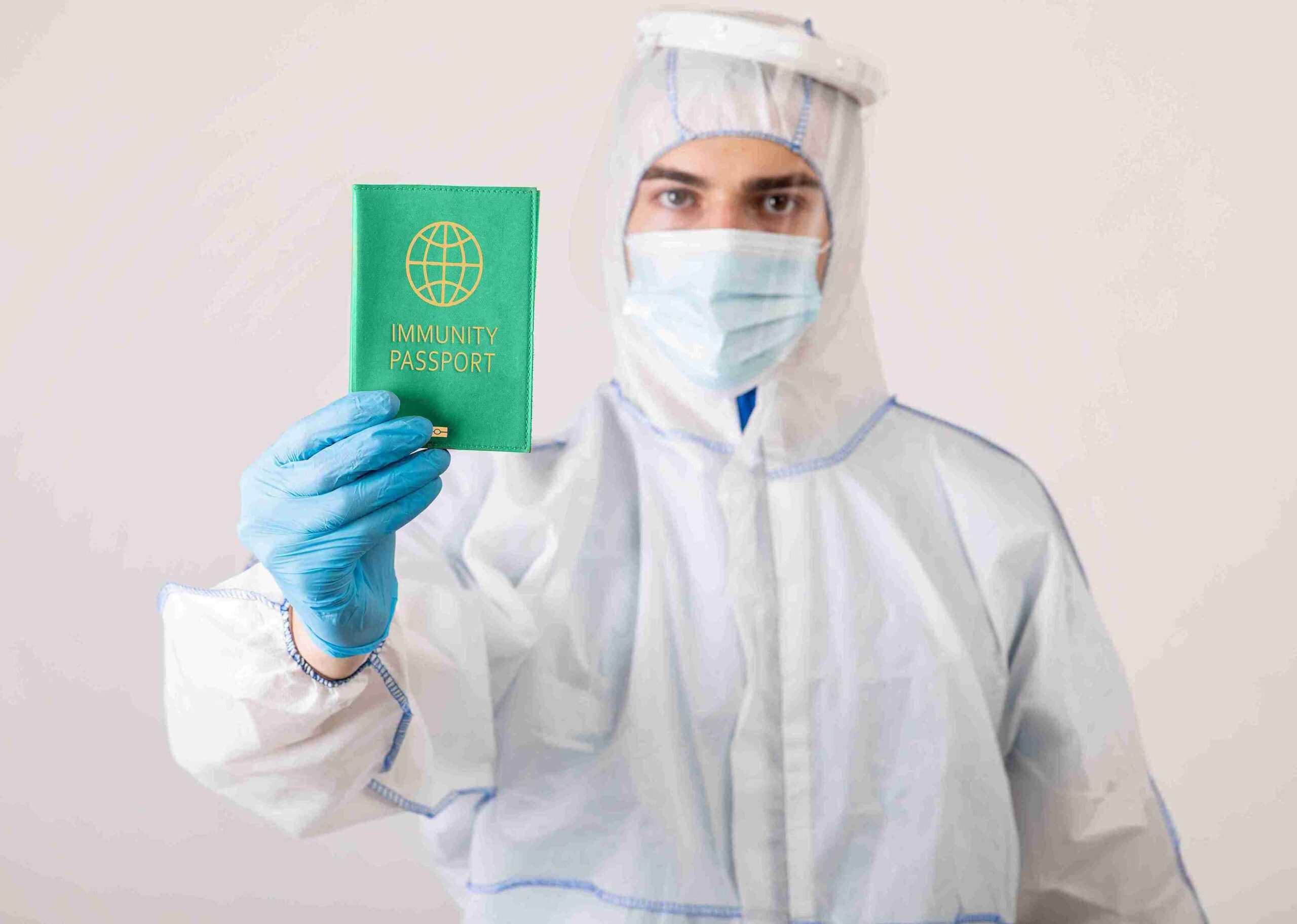 A man in a protective suit holds a green passport labeled 'Health & Care Worker Visa'