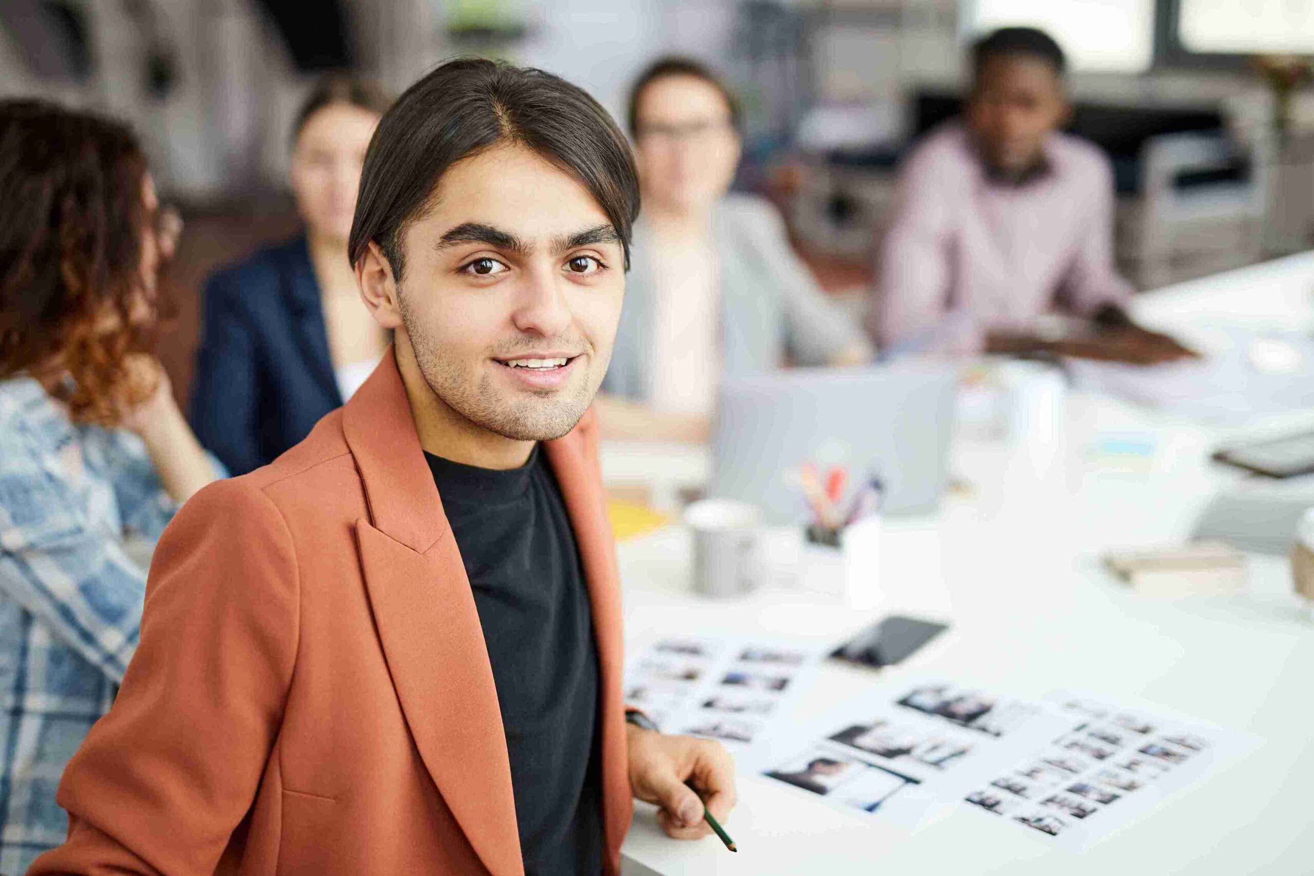 A man at a table with others, discussing ideas related to the new Start-Up in UK.