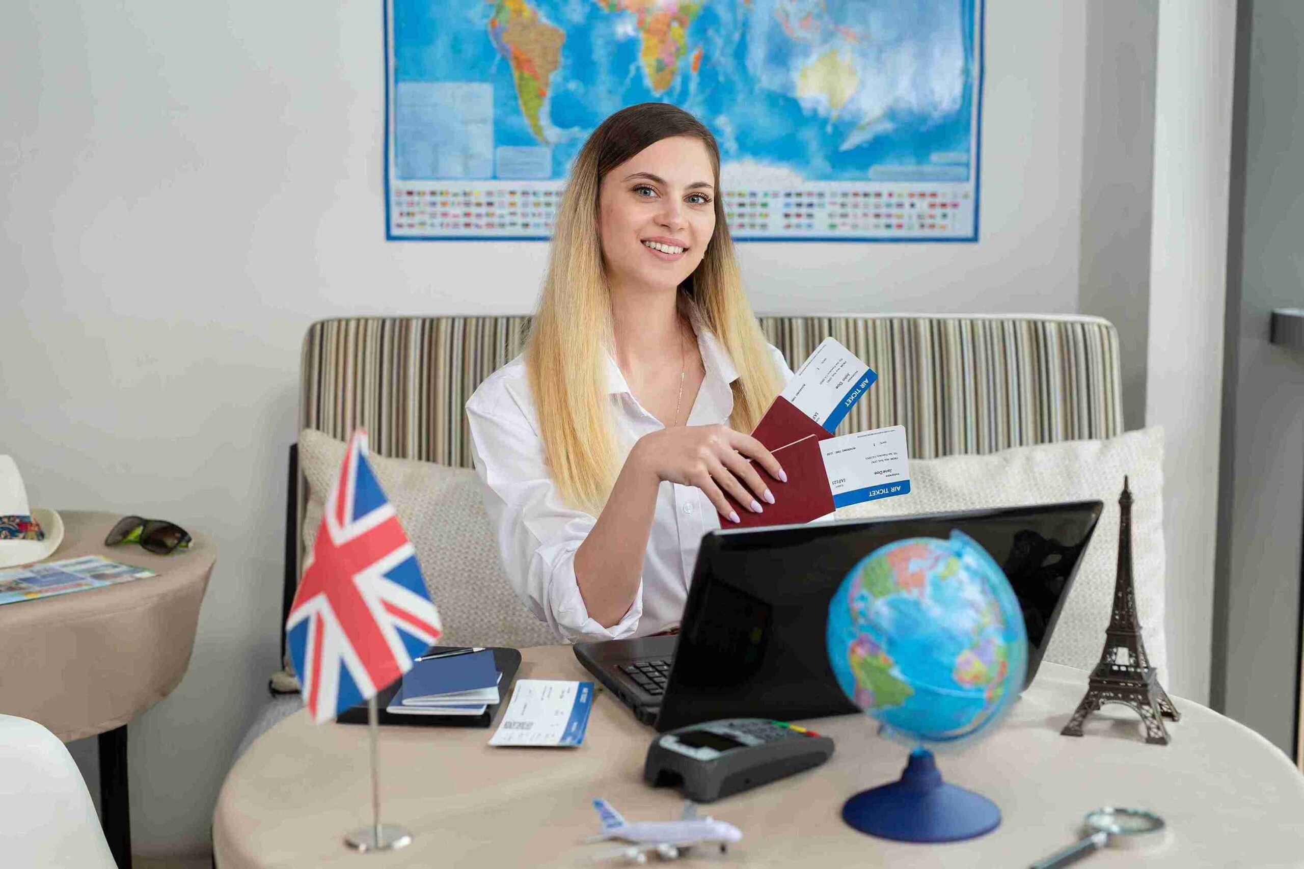 A woman at a desk with a laptop and passport, focused on her work, ready for travel or planning her next adventure.