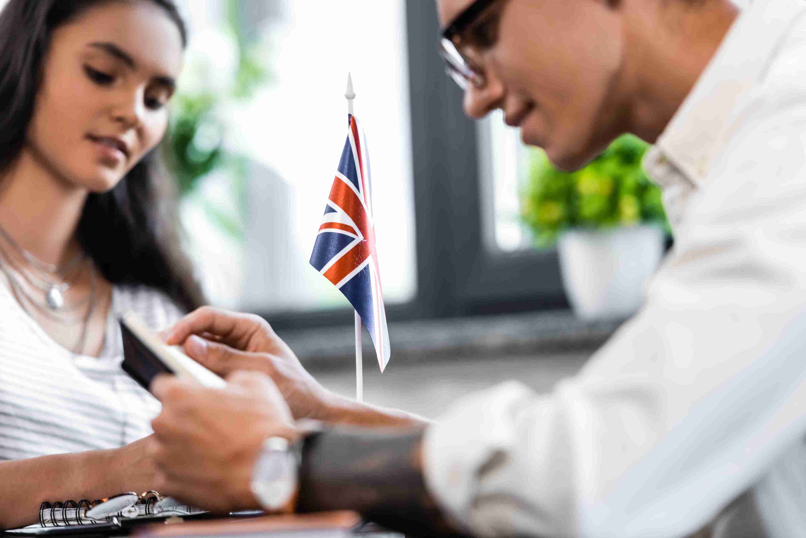 A man and woman sit at a table with a British flag, enjoying a moment together in the UK.