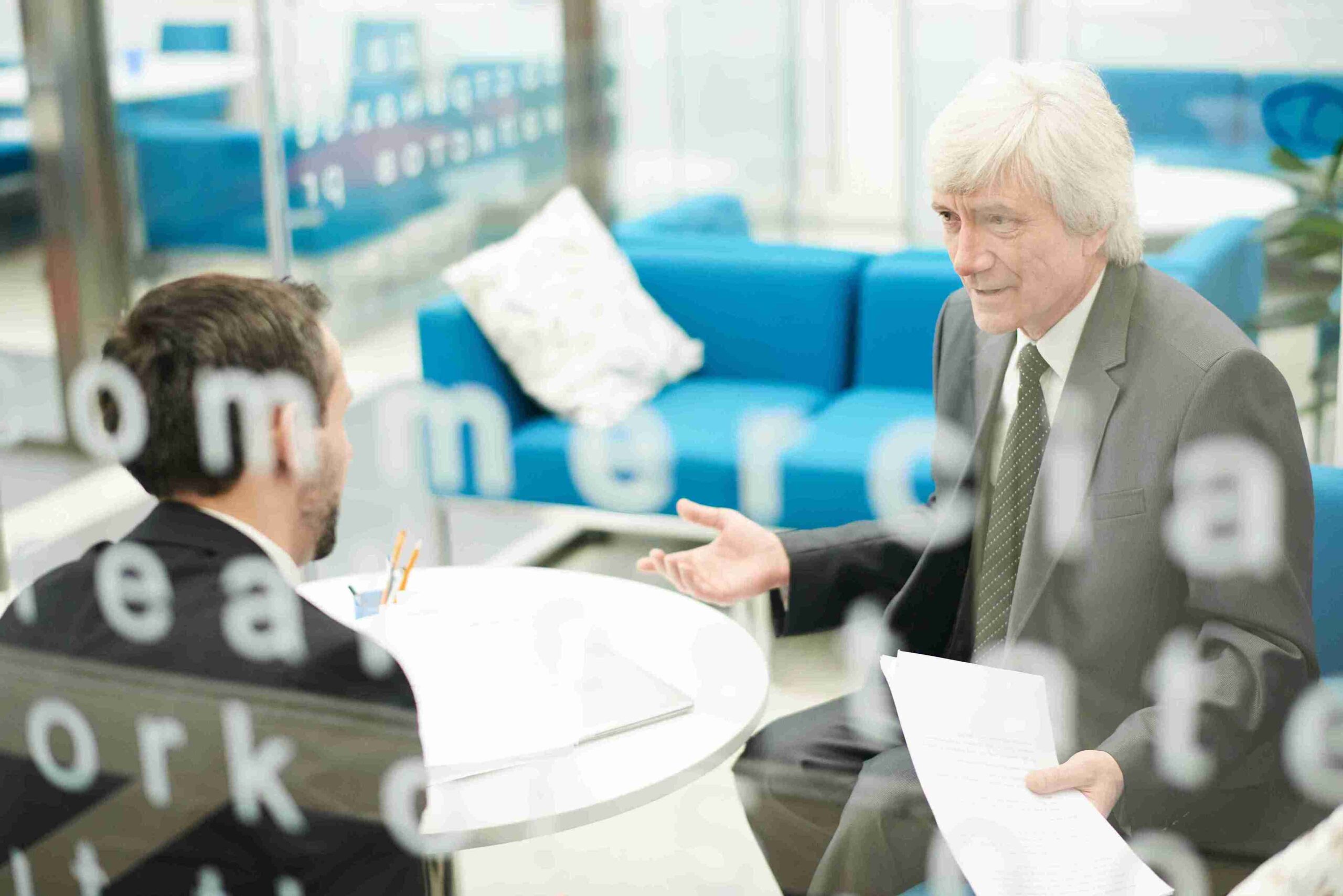 A man in a suit discusses business opportunities with another suited man, highlighting the Innovator Founder