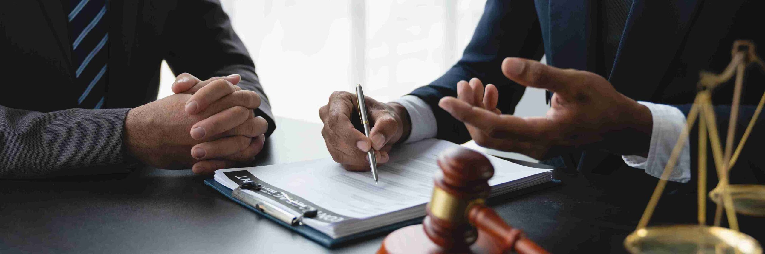 Two Lawyers reviewing documents at a table with gavel and scales, representing Solicitors providing expert UK legal advice in immigration.