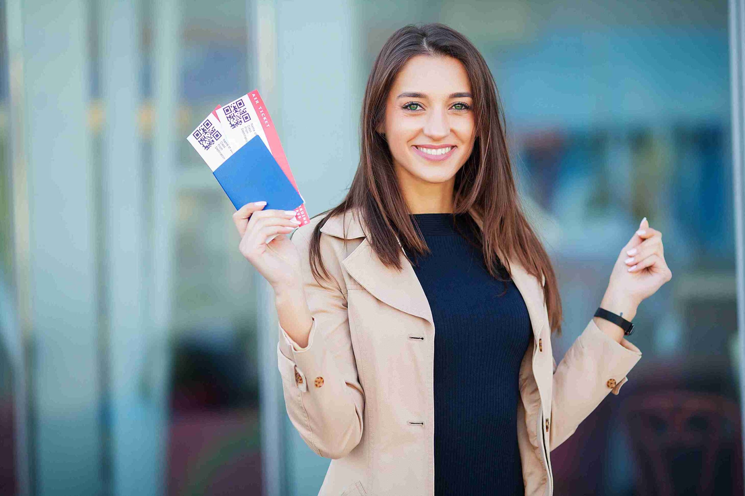 A woman smiles while holding a passport in one hand and a credit card in the other, ready for her travels.